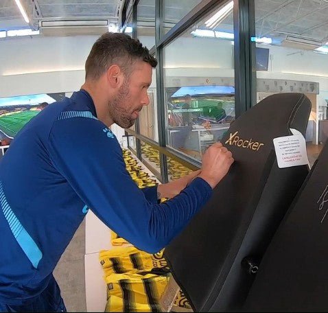 Ben Foster signing an autograph on an X Rocker Gaming Chair