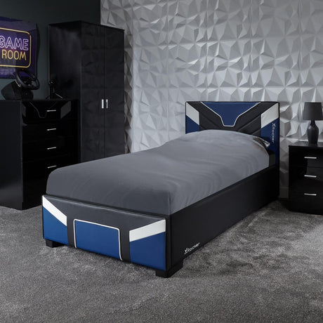 Bedroom with a bed, dresser, and gaming setup against a geometric wall.