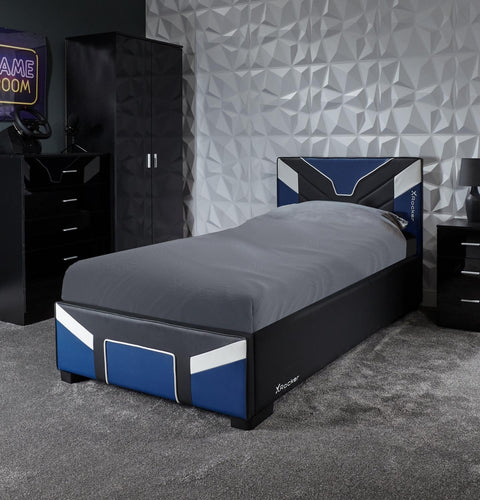 Bedroom with a bed, dresser, and gaming setup against a geometric wall.