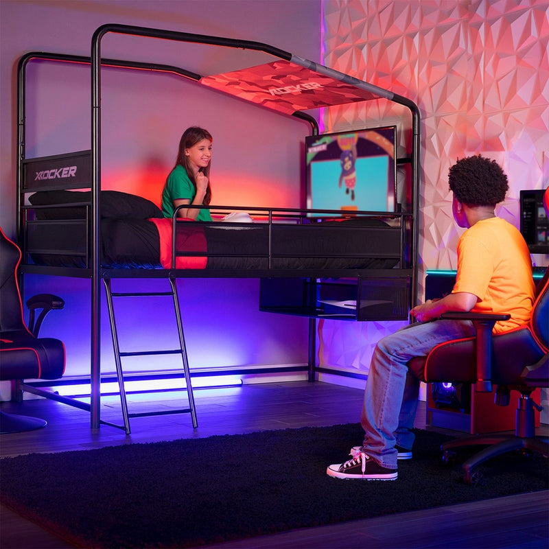 two teenagers in a gaming bedroom with a tv screen and chairs in a room with colorful lighting.