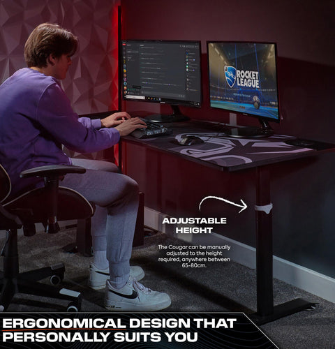 Person using a computer setup with an adjustable height desk in a room.