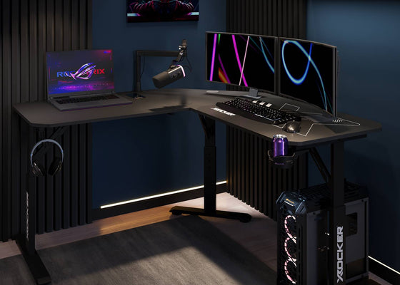 Gaming setup with a desk, laptop, monitors, and gaming equipment in a dark room.