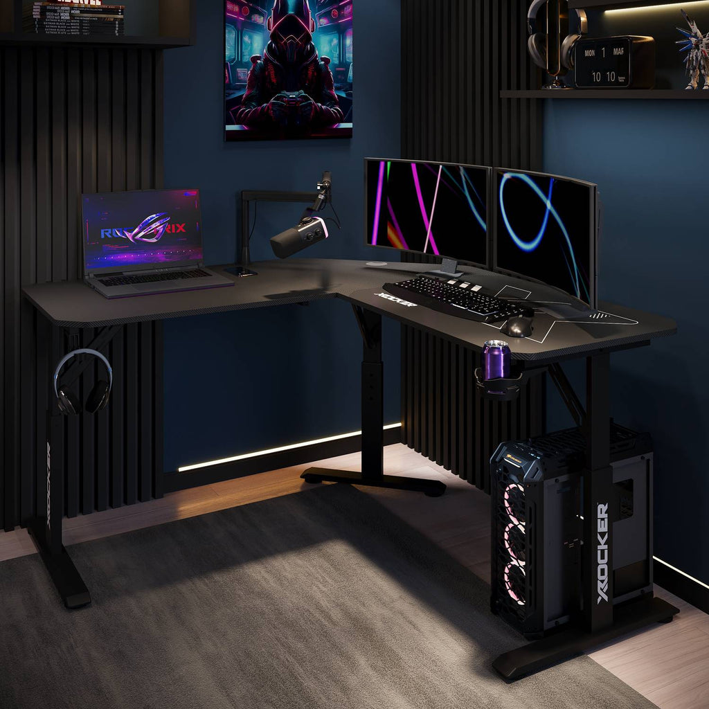 Gaming setup with a desk, laptop, monitors, and gaming equipment in a dark room.