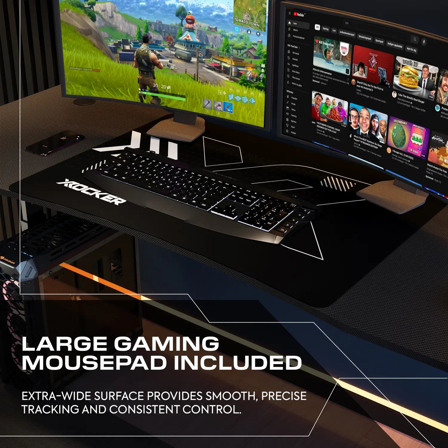 Gaming desk setup with large mousepad, keyboard, and monitors displaying a game.