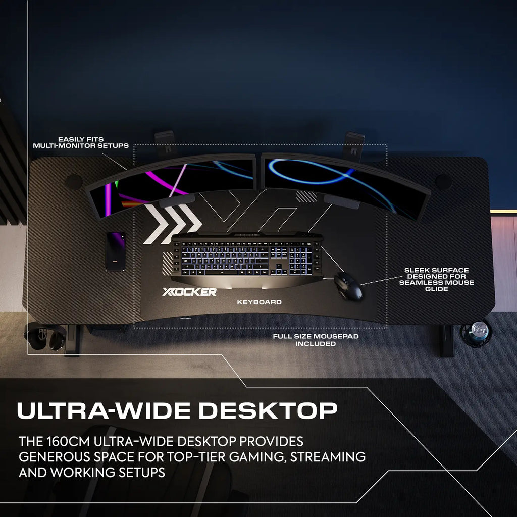 Gaming desk setup with keyboard, mousepad, and monitor stand on a dark background