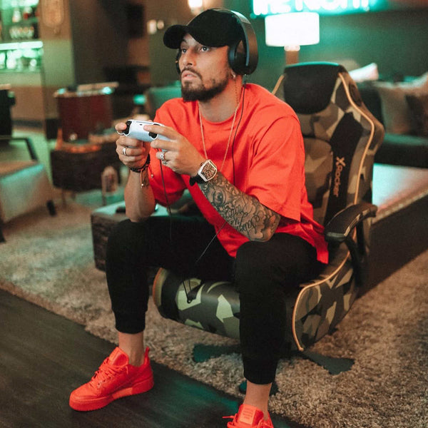 Man in red shirt and black cap playing video games in a gaming chair.