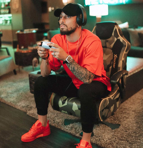 Man in red shirt and black cap playing video games in a gaming chair.