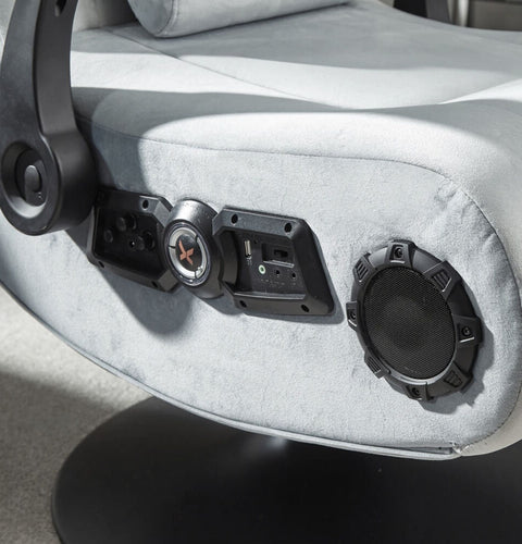 Close-up of a gaming chair with audio control panel and speakers.