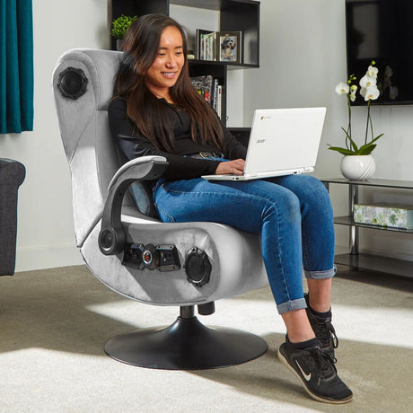 Woman using a laptop on a modern gaming chair in a living room setting.