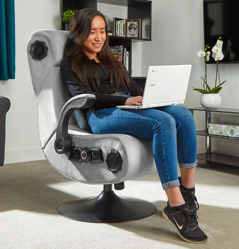Woman using a laptop on a modern gaming chair in a living room setting.