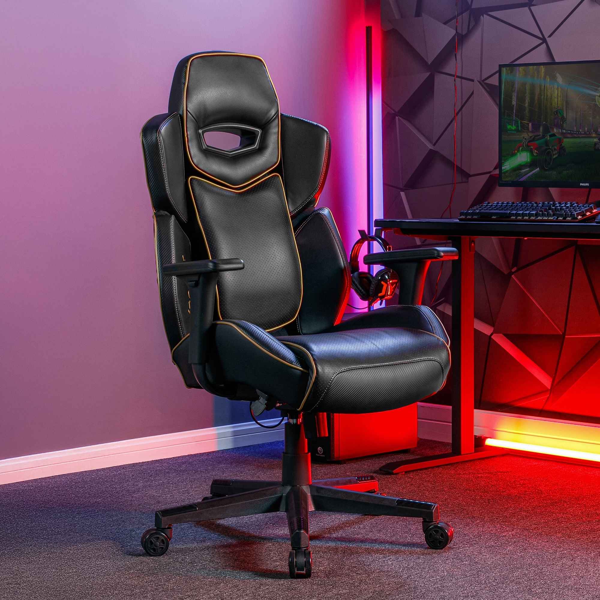 Gaming chair in a room with a desk and computer setup, featuring colorful lighting.