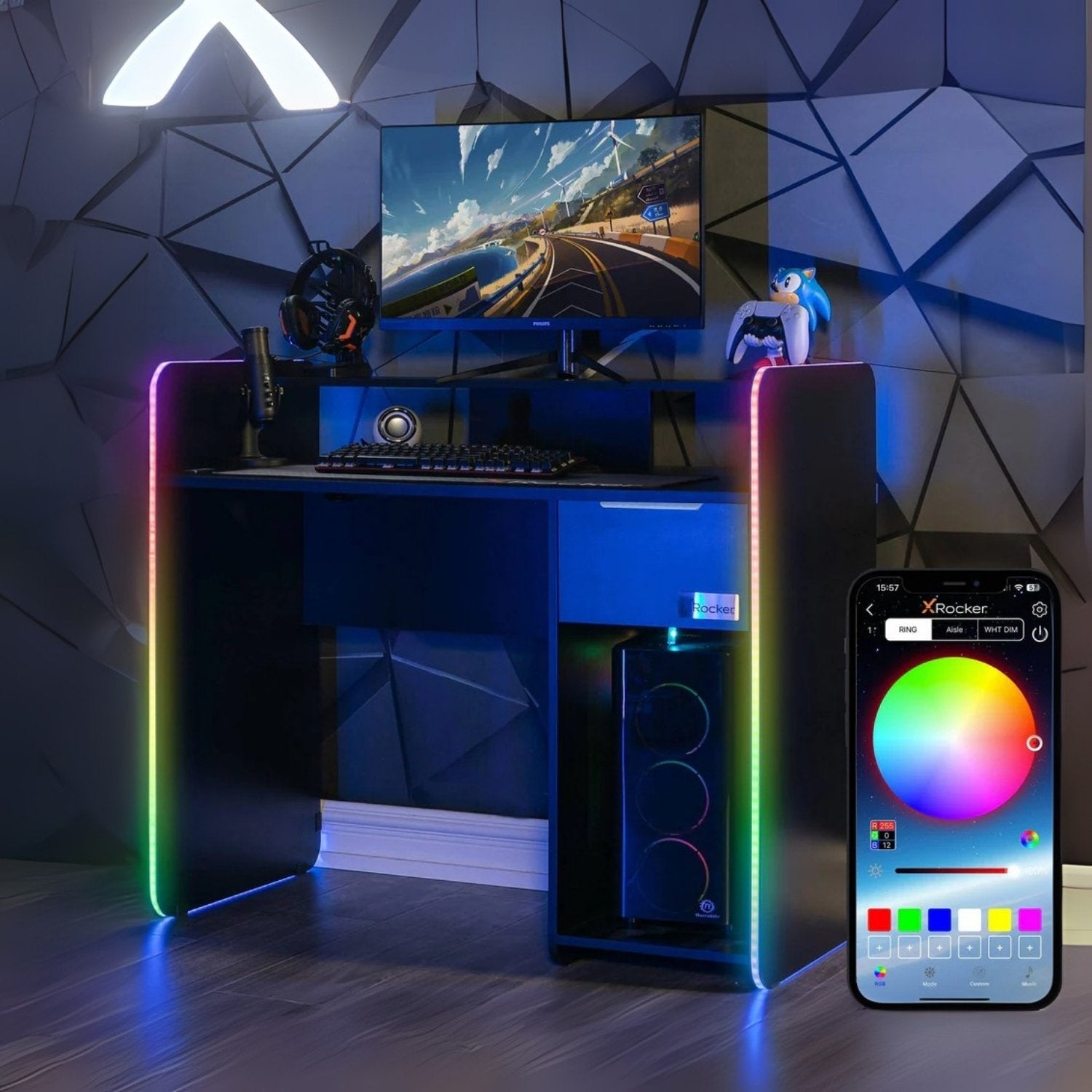 Gaming desk with RGB lighting, computer setup, and smartphone displaying lighting app.