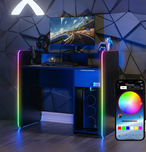 Gaming desk with RGB lighting, computer setup, and smartphone displaying lighting app.