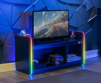 Gaming setup with a TV on a colorful stand against a geometric blue wall.