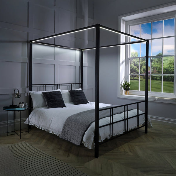 Modern bedroom with a black metal canopy bed and large window.