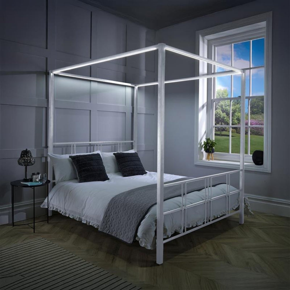 Four-poster bed in a bedroom with a window showing a garden view.