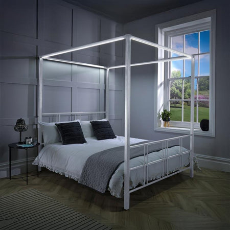 Four-poster bed in a bedroom with a window showing a garden view.