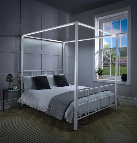 Four-poster bed in a bedroom with a window showing a garden view.