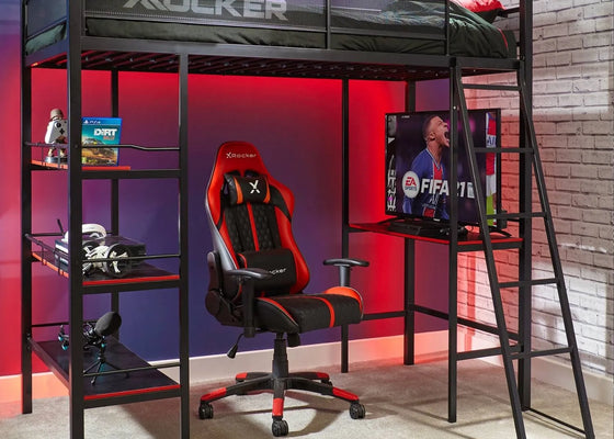 Gaming room setup with X rocker chair, desk, and computer setup.