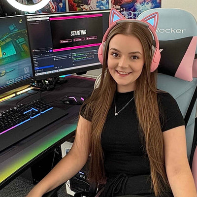 Person wearing pink cat ear headphones in a gaming setup with two monitors.