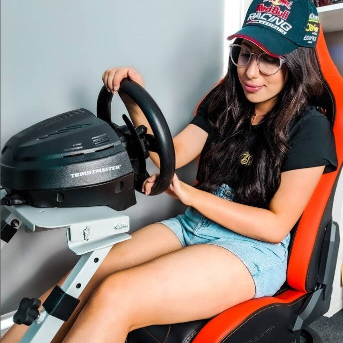 Person sitting in a gaming chair with a steering wheel and racing simulator setup.