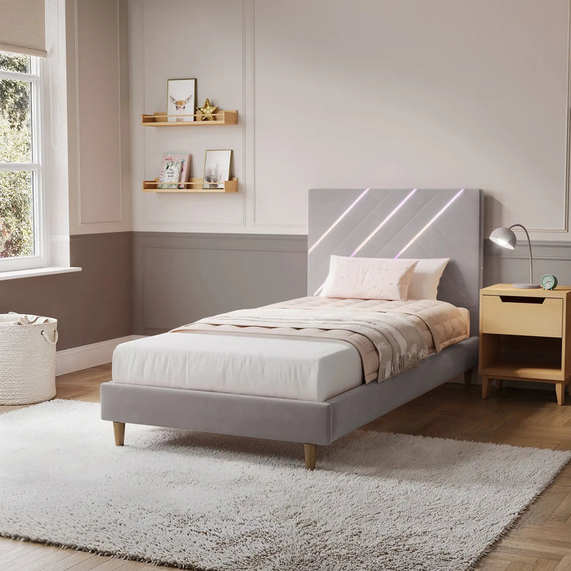 Modern bedroom with a gray upholstered bed, wooden nightstand, and shelves.