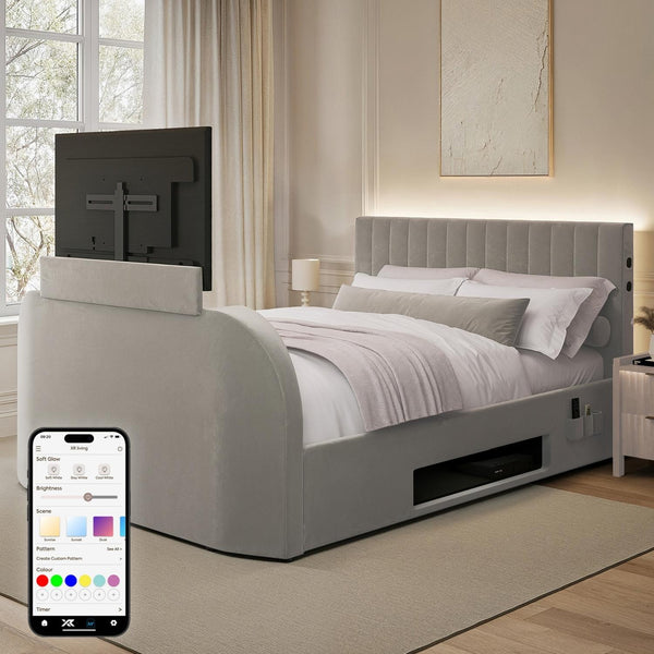 Gray upholstered bed with built-in TV and smartphone displaying app interface in a bedroom.