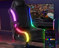 Gaming chair with RGB lighting and remote control in a room setup with a TV playing a racing game.