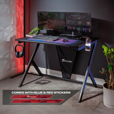 Gaming desk setup with multiple monitors, keyboard, mouse, and X rocker branding.