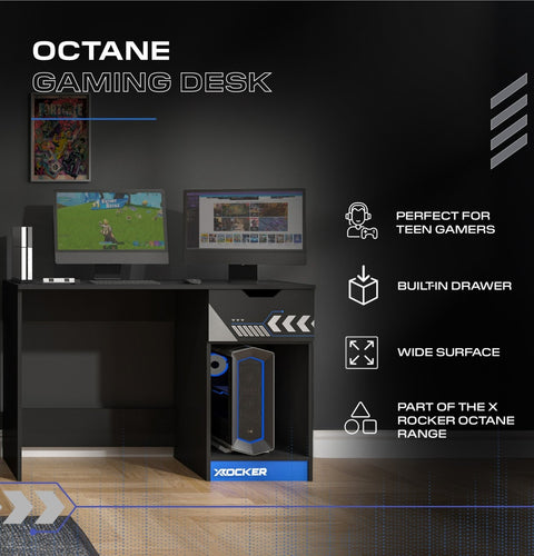 Gaming desk with computer setup on a dark wall background, featuring the X Rocker brand.