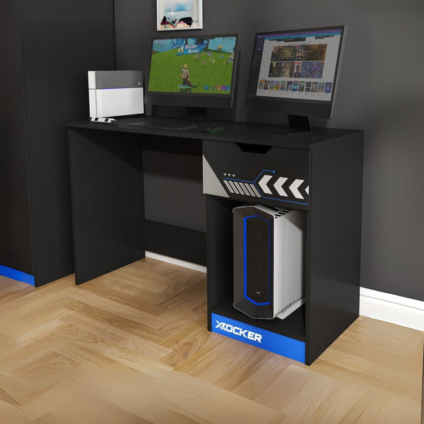 Black gaming desk with two monitors and a X rocker gaming chair on a wooden floor.