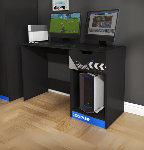 Black gaming desk with two monitors and a X rocker gaming chair on a wooden floor.