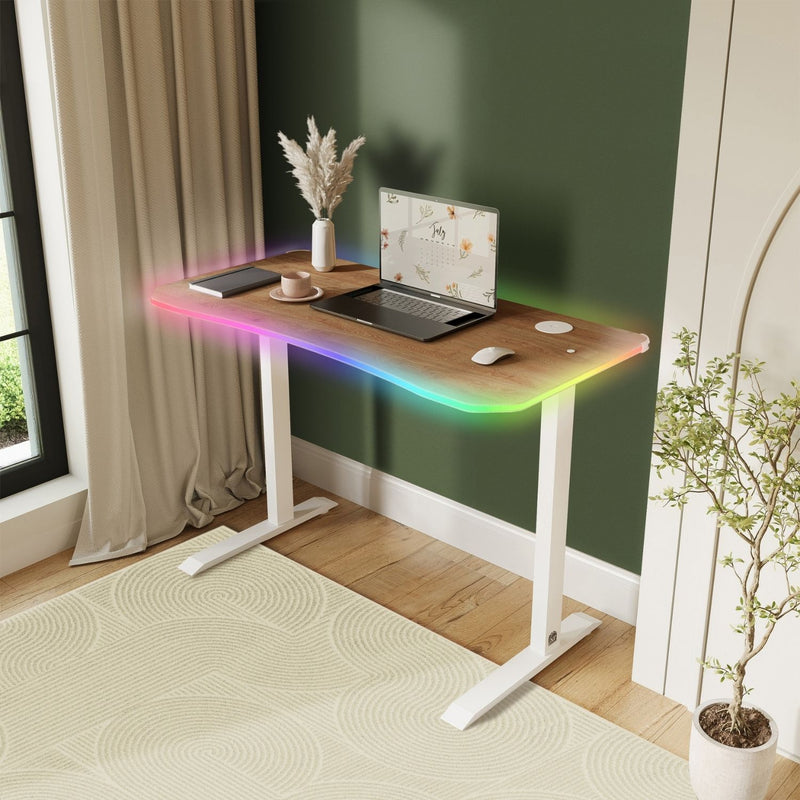 Wooden desk with laptop, mouse, and decorative items in a room with a window and plant.