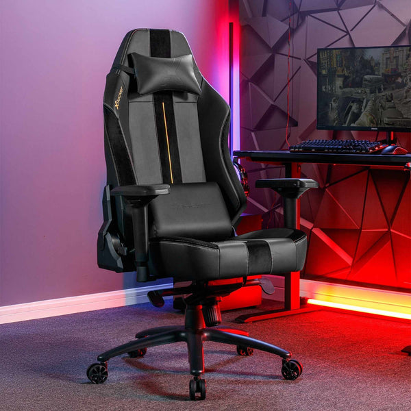 Gaming chair in a room with a desk and computer setup, illuminated by colorful lights.