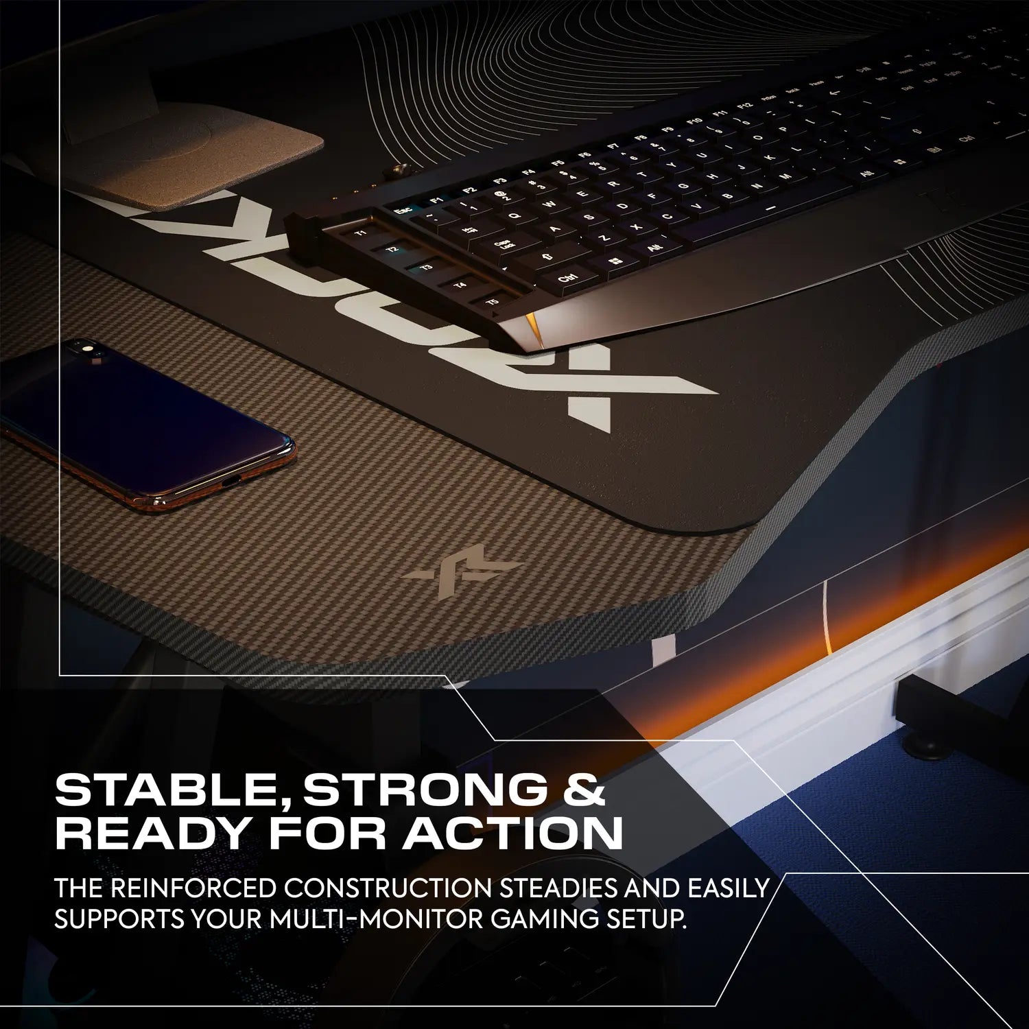 Gaming desk setup with monitor stand, keyboard, and phone on a dark surface.