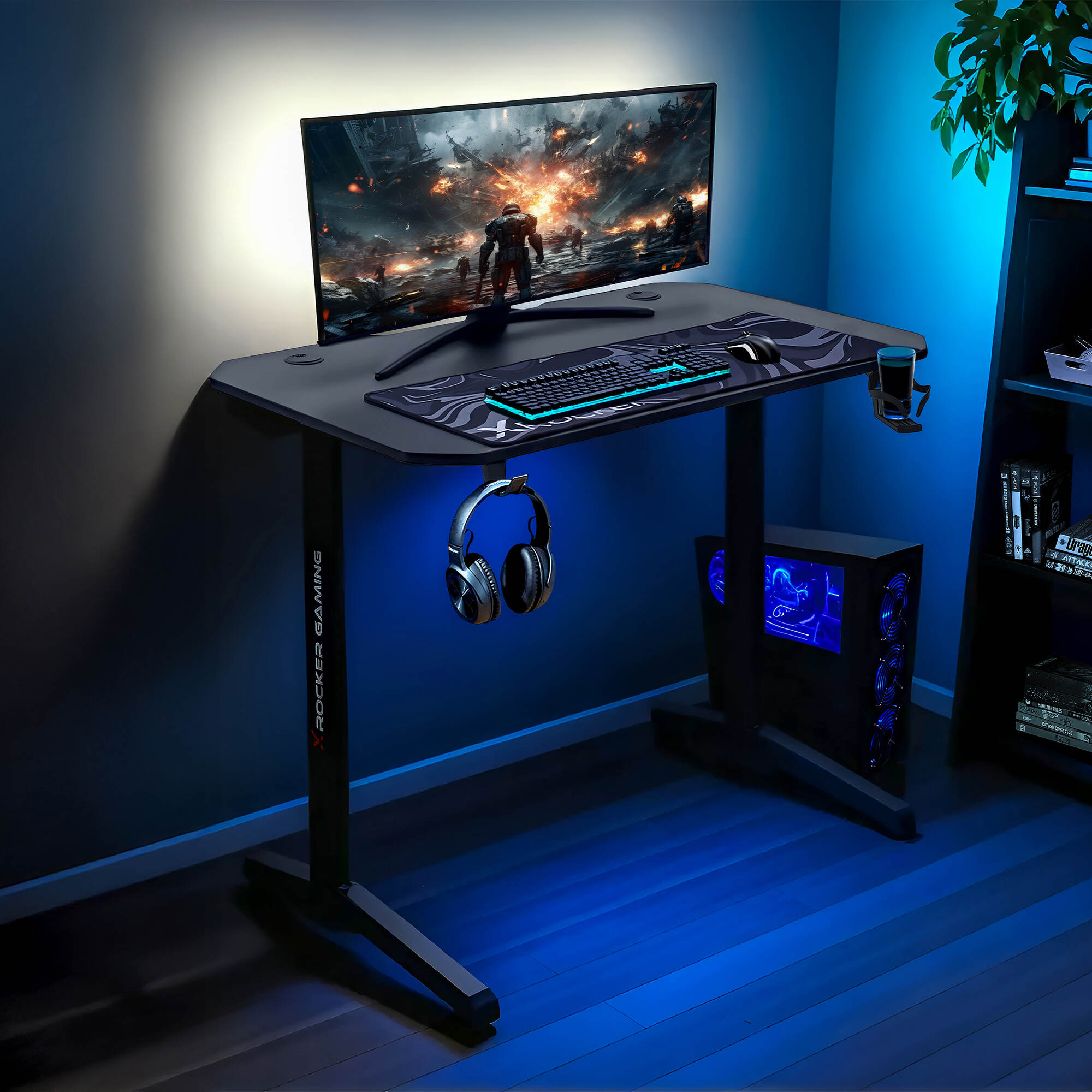 Gaming desk setup with monitor, keyboard, mouse, and headphones in a dark room.