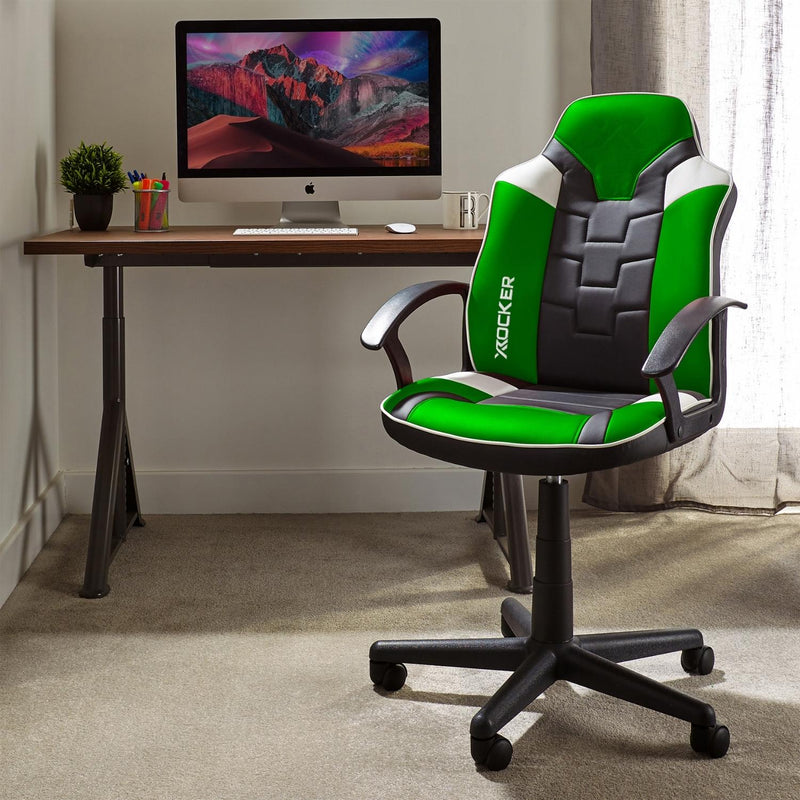 Green and black office chair in front of a computer desk with a monitor displaying a mountain scene.