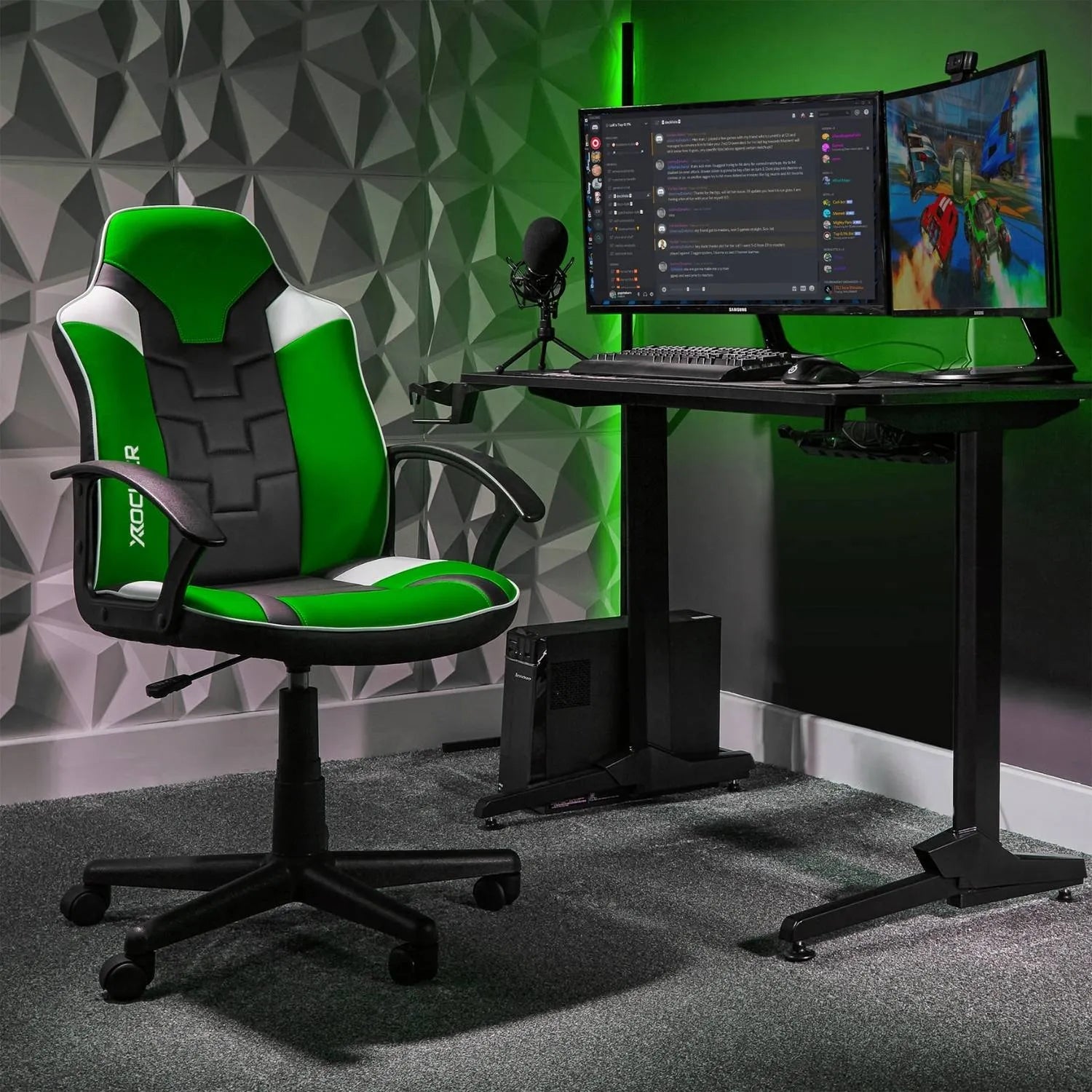 Gaming setup with green and black chair, desk, and dual monitors on a geometric patterned wall.