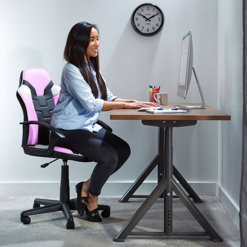 Person sitting at a desk with a computer, using a pink and black office chair.