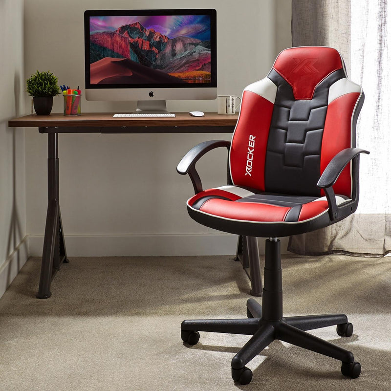 Red and black office chair in front of a computer desk with a monitor displaying a mountain scene.