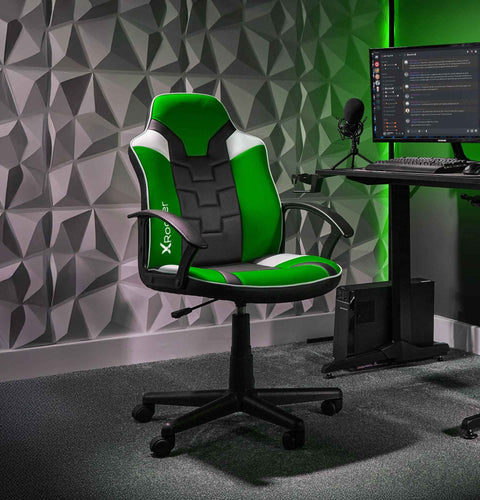 Gaming chair with green and black design in a room with geometric wall patterns and computer setup.