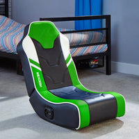 Black and green gaming chair in a room with a bed and colorful bedding.
