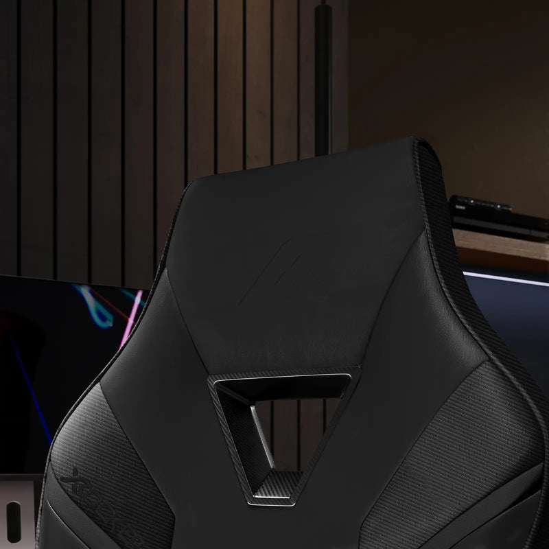 Black gaming chair with a modern design in a dimly lit room.