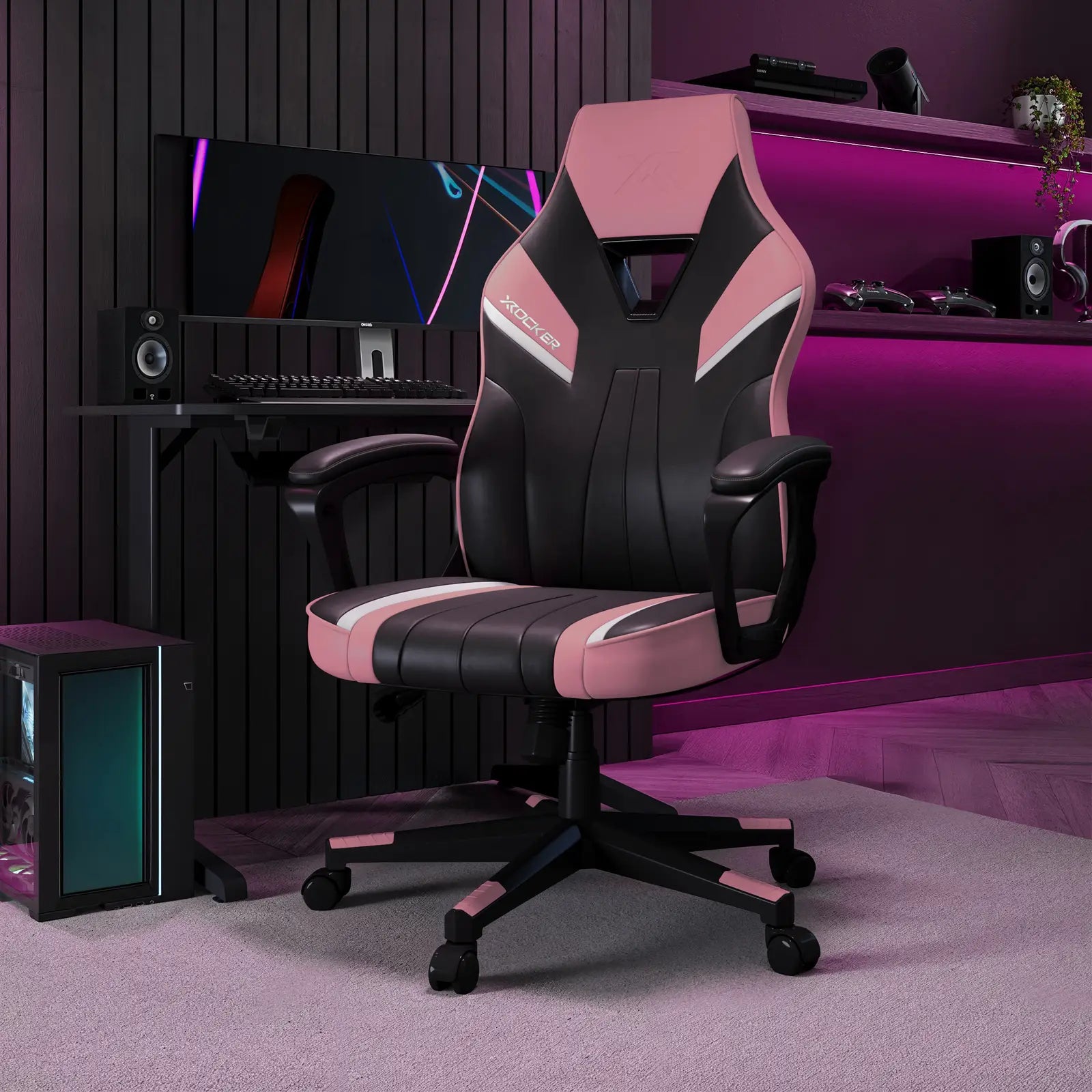 Gaming chair with black and pink design in a room setup with computer equipment.