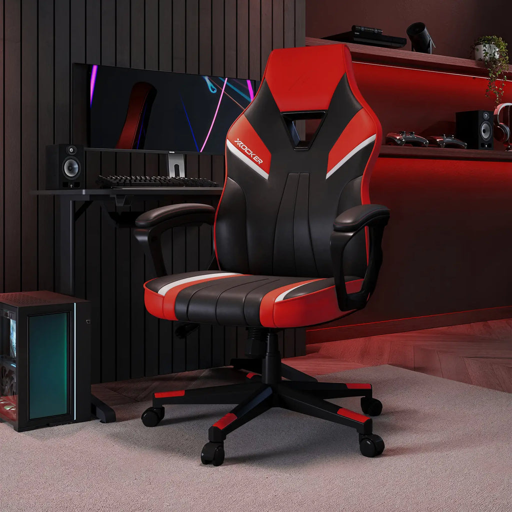 Gaming chair with red and black design in a room setup with computer equipment.