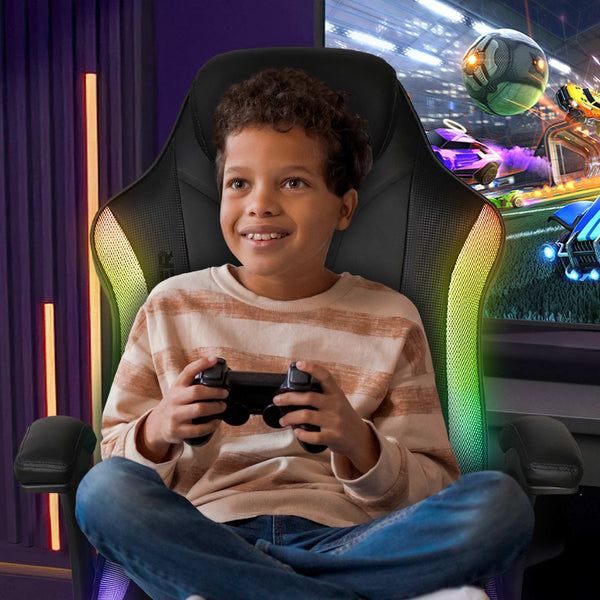 Child playing video games in a gaming chair with colorful lights and a screen in the background.