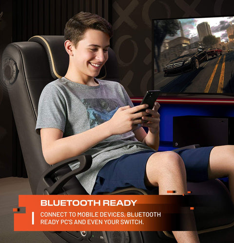 Person playing video games on a console with a gaming chair and TV in the background.