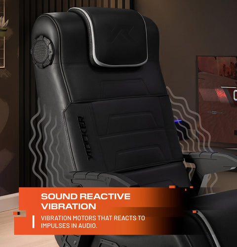 Black gaming chair with vibration motors labeled 'Sound Reactive Vibration' in a room setting.