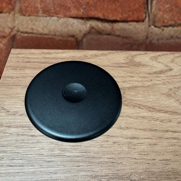 Black round object on a wooden surface with a brick wall background
