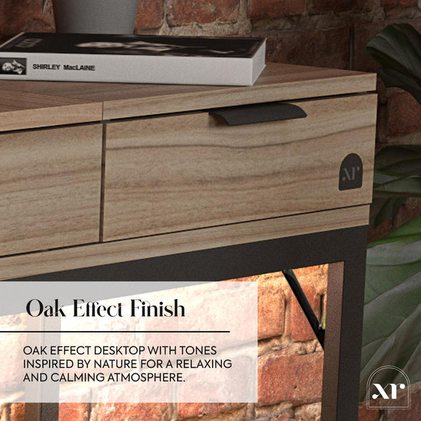 Wooden desk with oak effect finish, featuring a book on top, against a brick wall background.